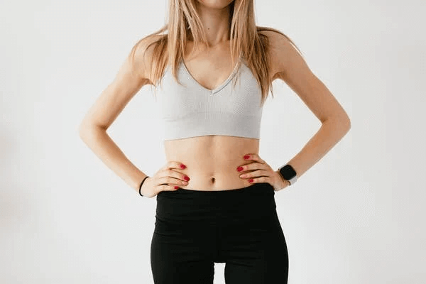 Sportswoman in sportswear and smart watch near wall